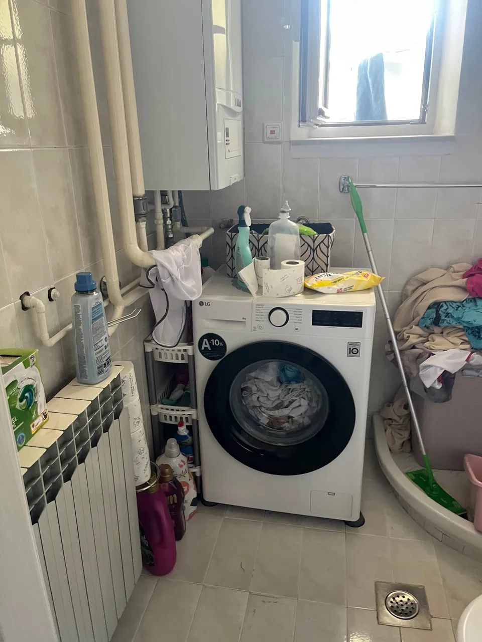 Perilica rublja, radijator i bojler u staroj kupaonici s prozorom