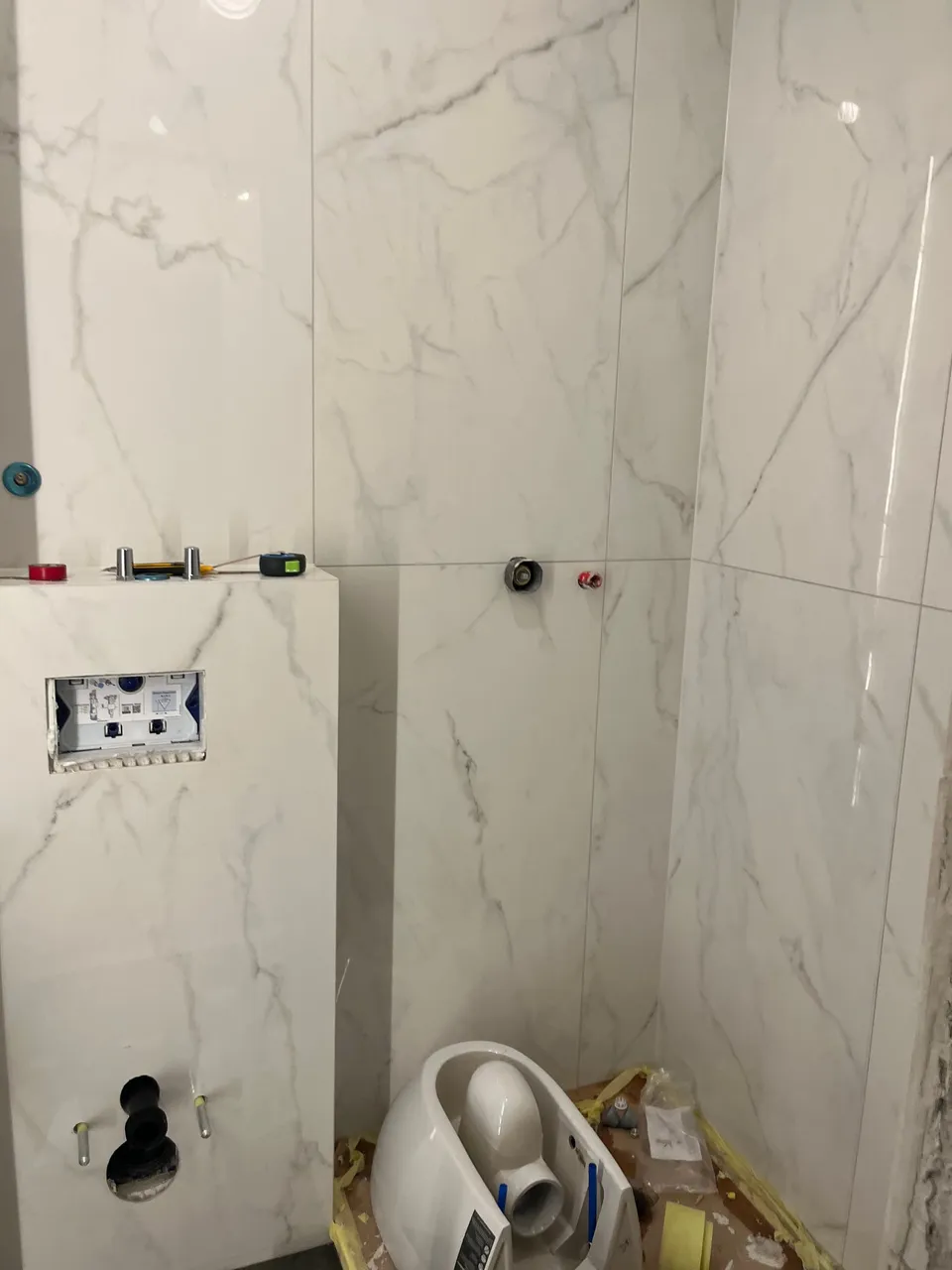 Zidovi obloženi pločicama mramornog izgleda i ugrađena konstrukcija za viseći WC